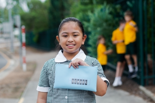 Aussie kid of Filipino ethnicity holding out a pencil case ready for going back to school - Australian Stock Image