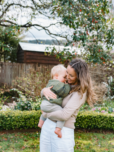 Aussie mum carrying toddler son in the garden - Australian Stock Image