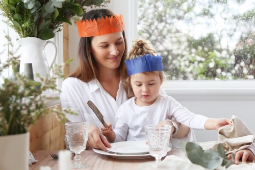 Mother and daughter at table wearing Christmas hats