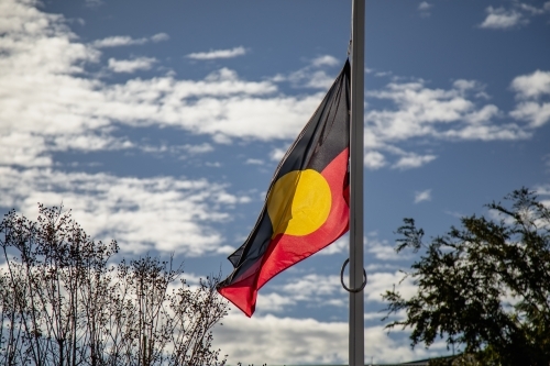 Australian Aboriginal flag flying in the wind with blue sky background - Australian Stock Image