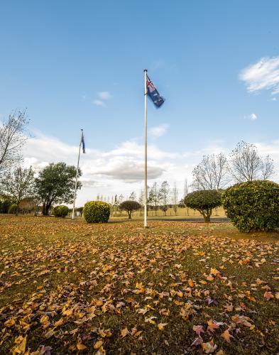 Australian flag moving in breeze with autumn eaves under flag pole