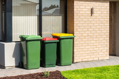 Australian garbage wheelie bins with colourful lids for recycling, general and green waste provided - Australian Stock Image