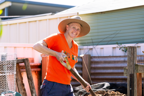 Australian woman in backyard garden ready to turn soil in compost container - Australian Stock Image
