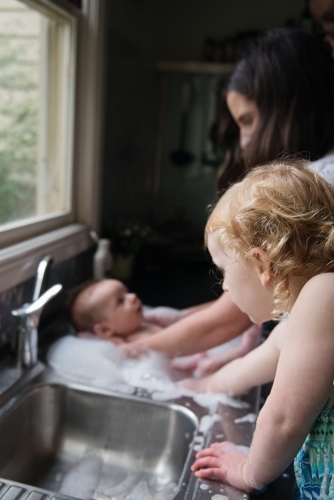 Baby bathtime in kitchen sink - Australian Stock Image