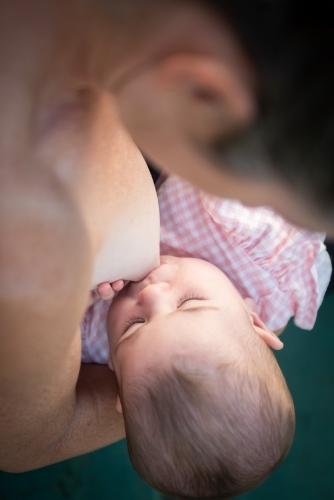 Baby breast feeding from her mother. - Australian Stock Image