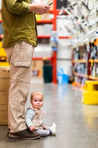 Baby sitting at fathers feet in hardware store