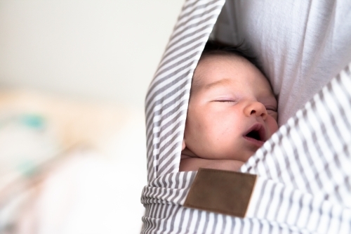 Baby sleeping in carrier - Australian Stock Image