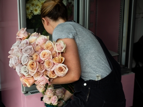 Back view of female florist with a large bunch of beautiful pastel coloured roses