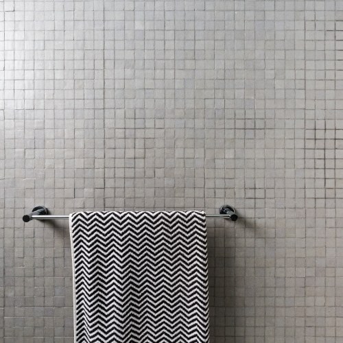 Background of mosaic square wall tiles with chevron towel on chrome towel rail - Australian Stock Image