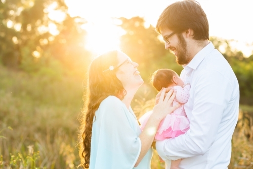 Backlit joyful family with newborn baby girl outside in Aussie sunlight