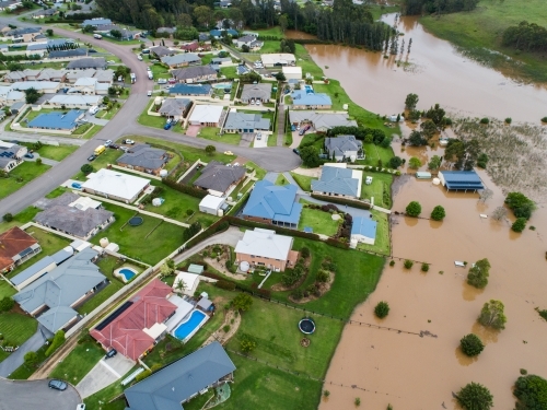 Backyards of homes full of brown floodwater from river backflow