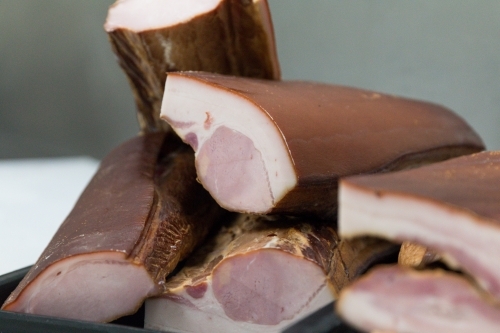 Bacon ready to be sliced in butchers store - Australian Stock Image