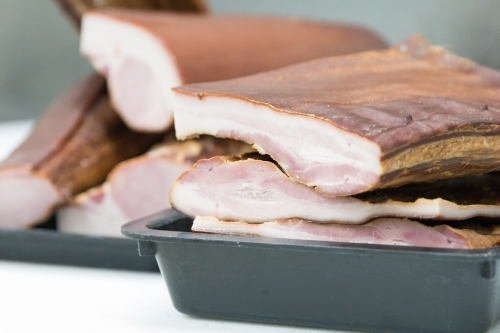 Bacon waiting to be sliced in butcher shop - Australian Stock Image