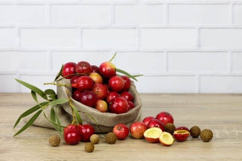 Bag of quandongs and leaves on wooden bench - Australian Stock Image