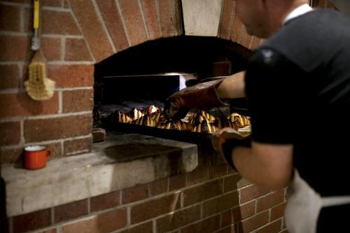 Baker putting croissants into oven - Australian Stock Image