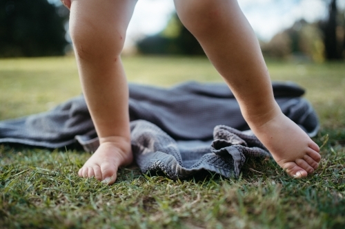 Bare toes of a toddler on the grass with a dropped towel - Australian Stock Image