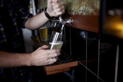 Bartender pouring drink on tap at local craft beer bar