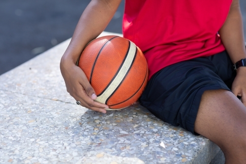 basketball being held by player on sidelines - Australian Stock Image