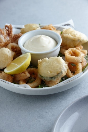 Battered deep fried seafood and vegetables on plate with dip - Australian Stock Image