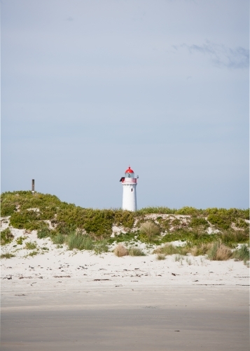 beach and sand dune with lighthouse in background - Australian Stock Image