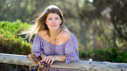 Beach girl leaning on wooden railing - Australian Stock Image