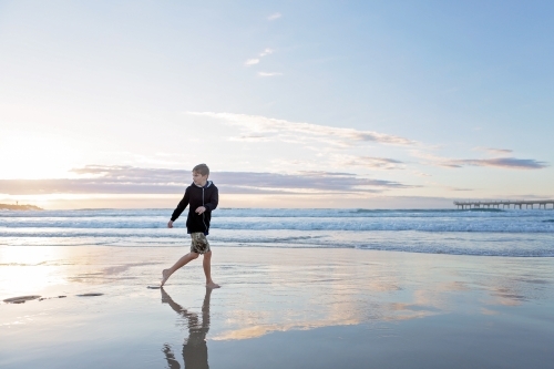 Beach reflections with boy running on wet sand