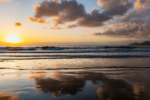 Beach scene at sunrise with waves and sand - Australian Stock Image
