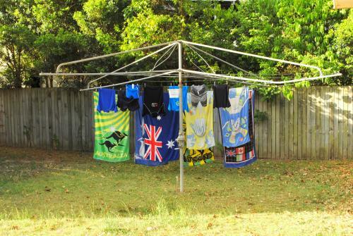 Beach towels and swimwear are hanging on a Hills Hoist in a suburban garden
