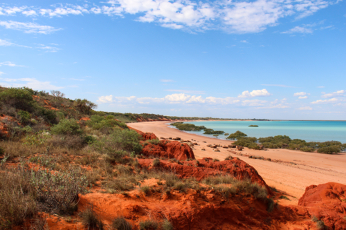 Beach with red cliffs, red sand, and aqua water - Australian Stock Image
