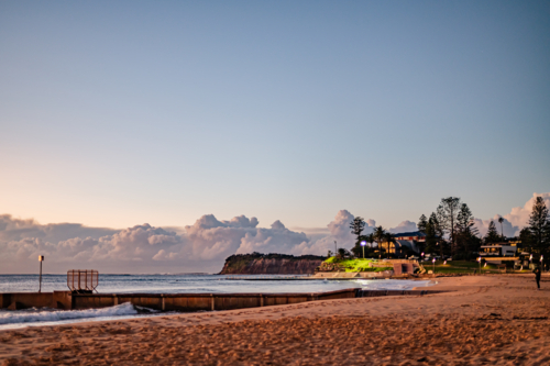 Beach with Seawall and Distant Cliffs at Sunrise - Australian Stock Image
