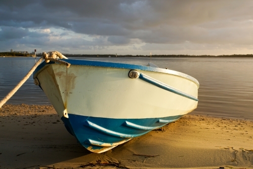 Beached boat sunlit with stormy sky
