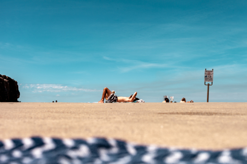 Beachgoers bathing under the sun while lying on the sand. - Australian Stock Image