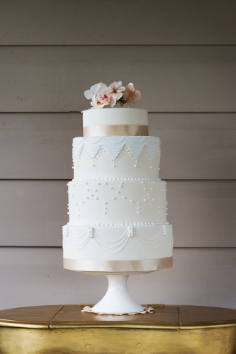 beautiful hollywood glam white wedding cake with pastel pink flowers and lots of piping