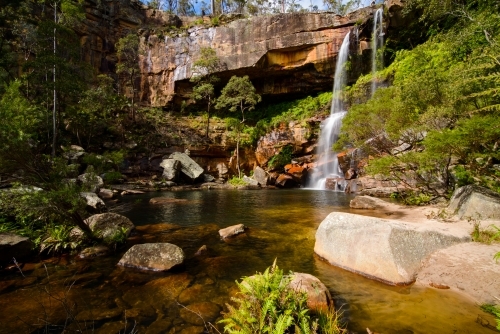 Beautiful scenic falls with colourful orange sandstone and green ferns - Australian Stock Image