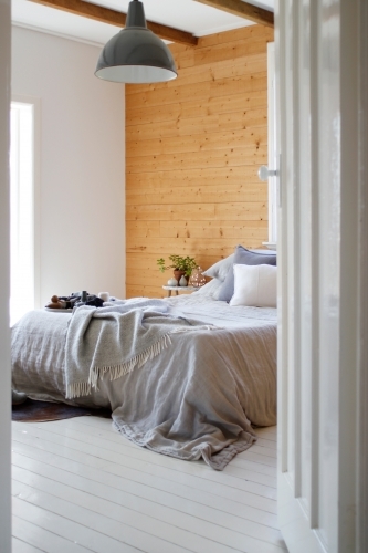 Bedroom through doorway with grey linen on bed and coffee table