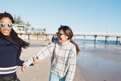 Best friends spending time on the beach laughing - Australian Stock Image