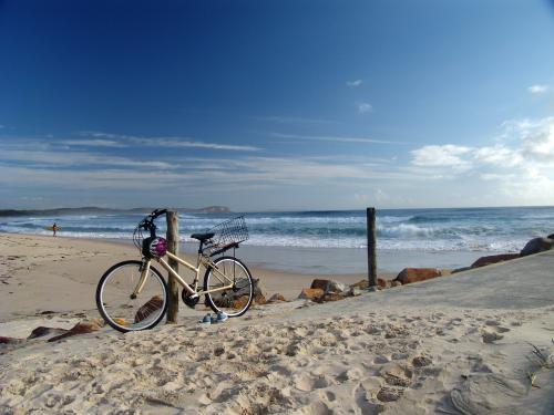 Bicycle parked at a post by the beach