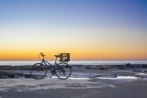 Bicycle parked on beach at sunset - Australian Stock Image