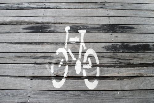 Bicycle sign in white paint on wooden boardwalk
