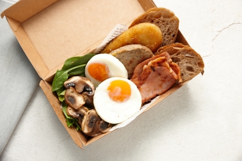 big breakfast in a box composed of eggs, toast, tomato, mushroom and greens - Australian Stock Image