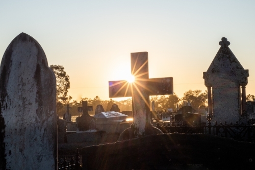 big cross and tombstones at the cemetery during sunrise/sunset - Australian Stock Image