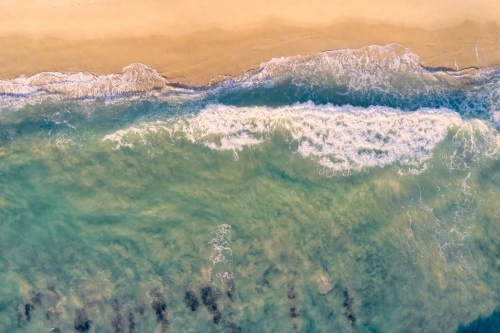 Bird's eye view of a small wave washing ashore on a Western Australian beach. - Australian Stock Image