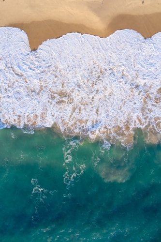 Bird's eye view of a wave washing ashore with lots of froth on a Western Australian beach. - Australian Stock Image