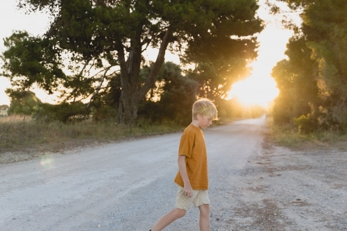 Blond boy exploring along gravel country road - Australian Stock Image