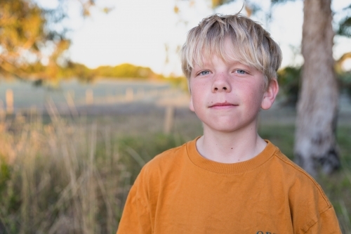 Blond scruffy boy on farm field - Australian Stock Image