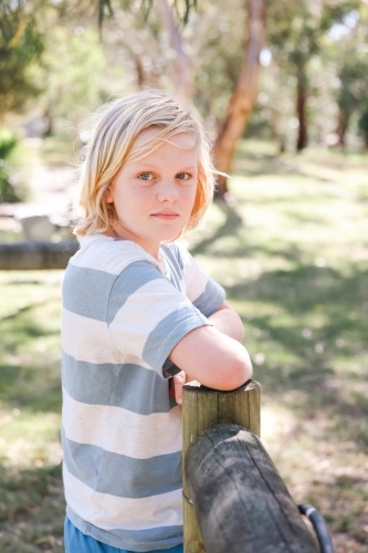 Blonde pre-teen boy leaning on fence on farm - Australian Stock Image