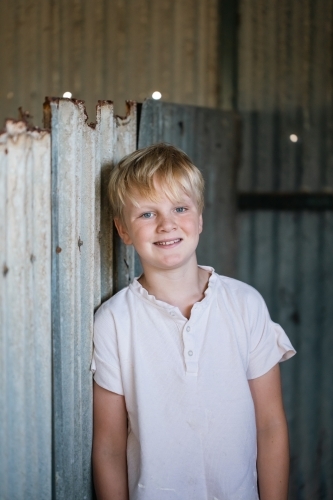 blonde pre-teen boy with relaxed pose standing in rustic county setting - Australian Stock Image