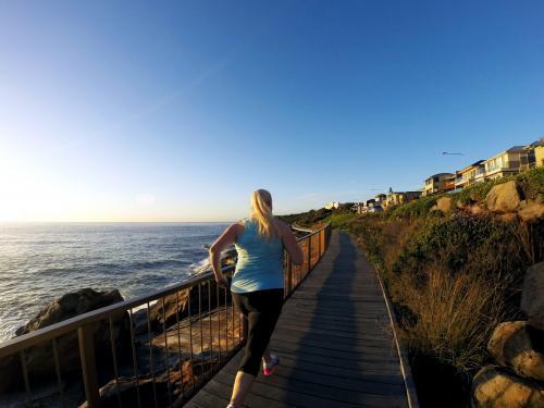Blonde woman running along ocean boardwalk at sunrise