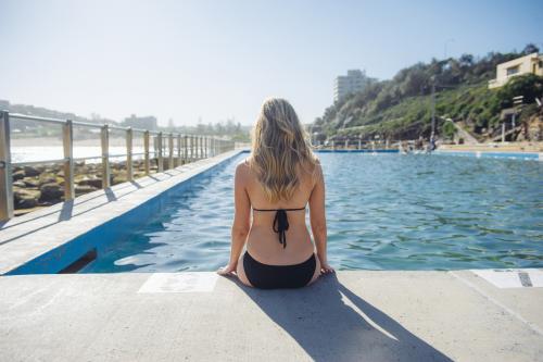 Blonde Woman sitting on the edge of an ocean pool