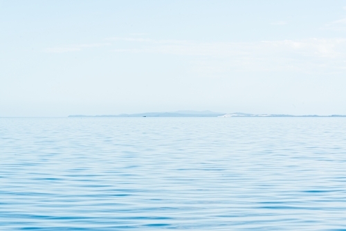 Blue and blue sky with hazy islands on horizon - Australian Stock Image